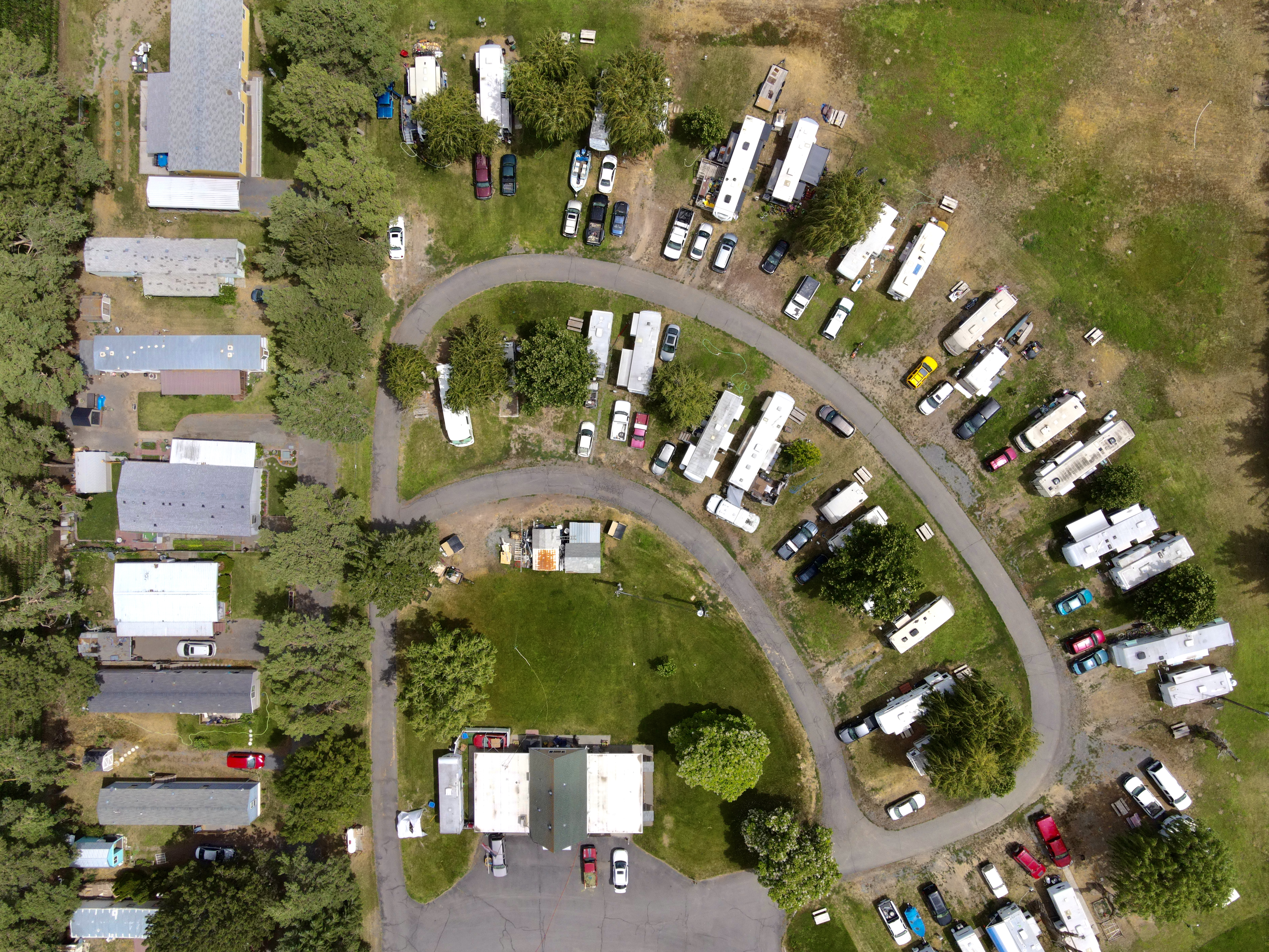 Straight-down aerial of Willows Trailer Village showing the curved interior road, occupied RV sites, lawns, and mature shade trees